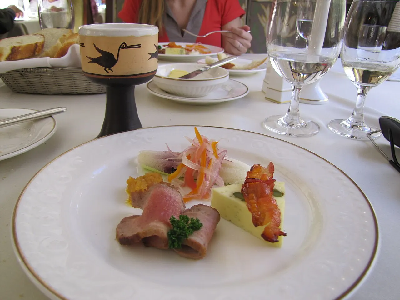 A fine-dining plate and table set for two with wine glasses aboard the Belmond Hiram Bingham luxury train