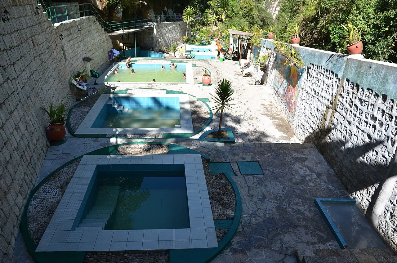 Bathers in the terraced thermal pools above Aguas Calientes with cliffs and forest behind