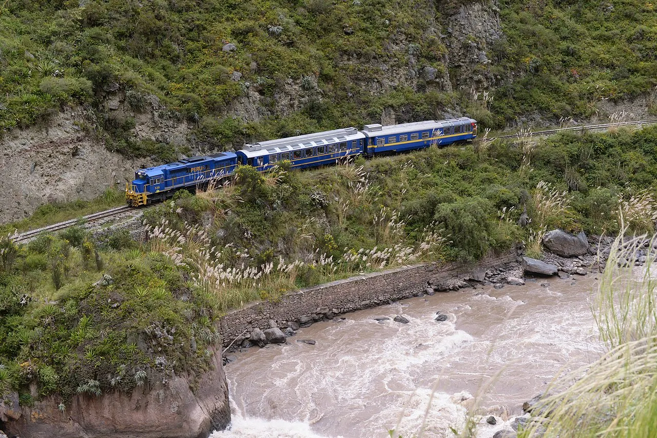 A Machu Picchu-bound PeruRail train threading the Urubamba gorge below cloud-forest cliffs