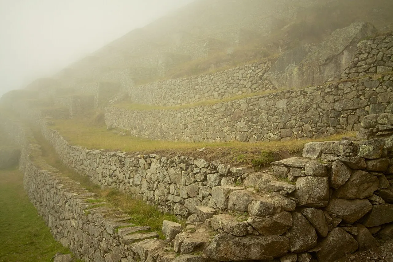 Morning mist sweeping across the upper terraces of Machu Picchu, half the ruins hidden